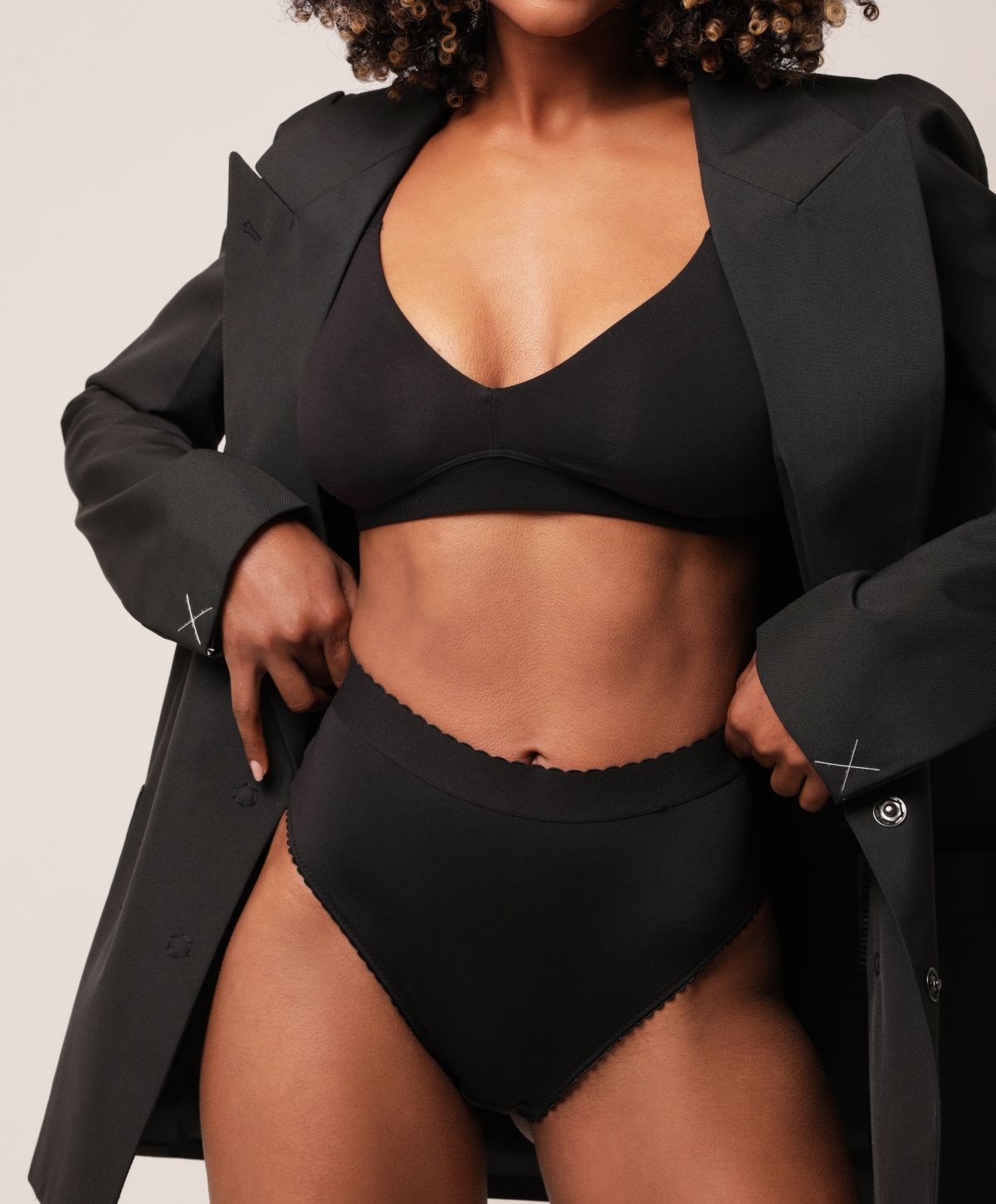 Model wearing black lingerie and oversized blazer.
