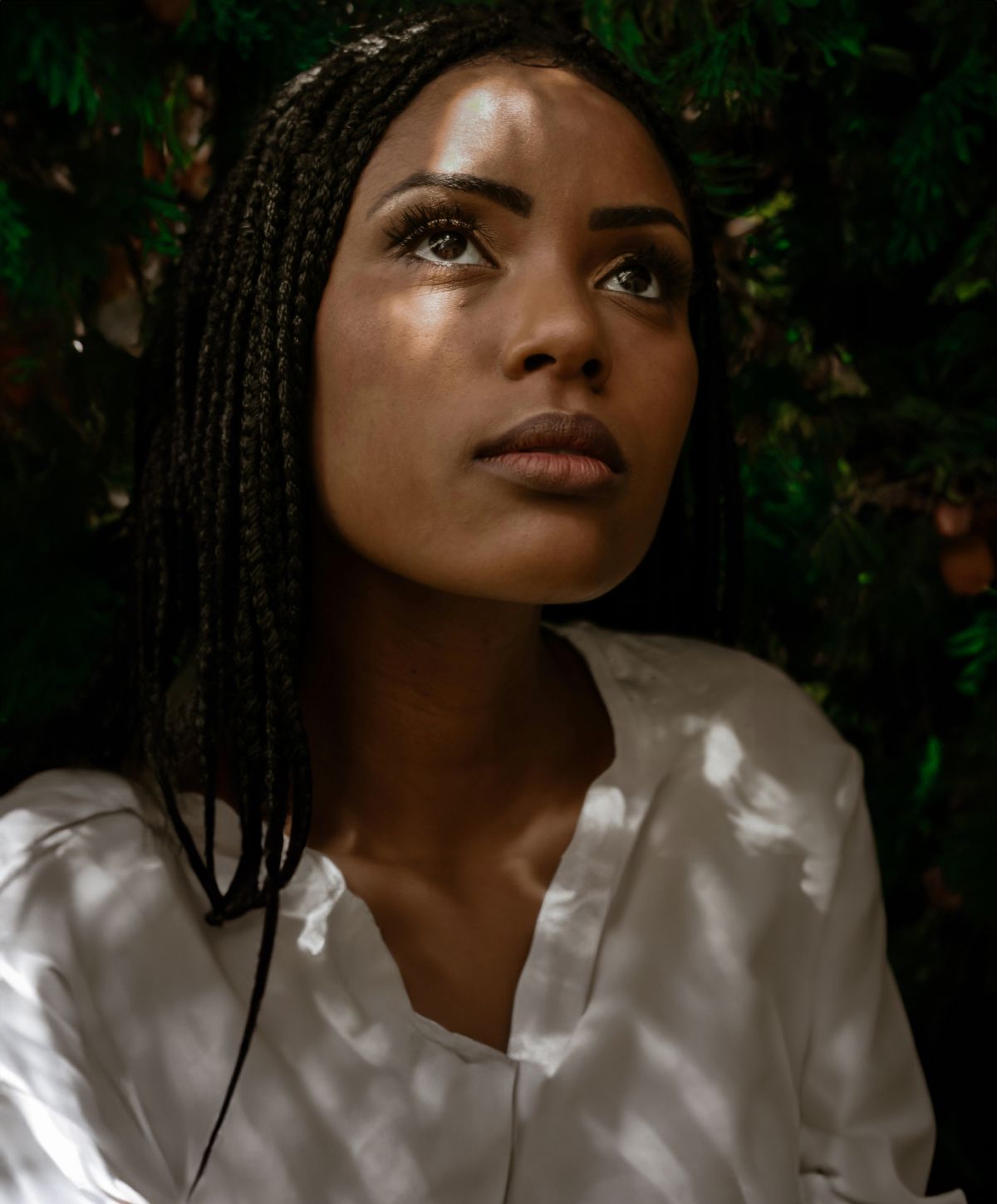 Farmington deep plane facelift model with braids gazing upwards in shadows.