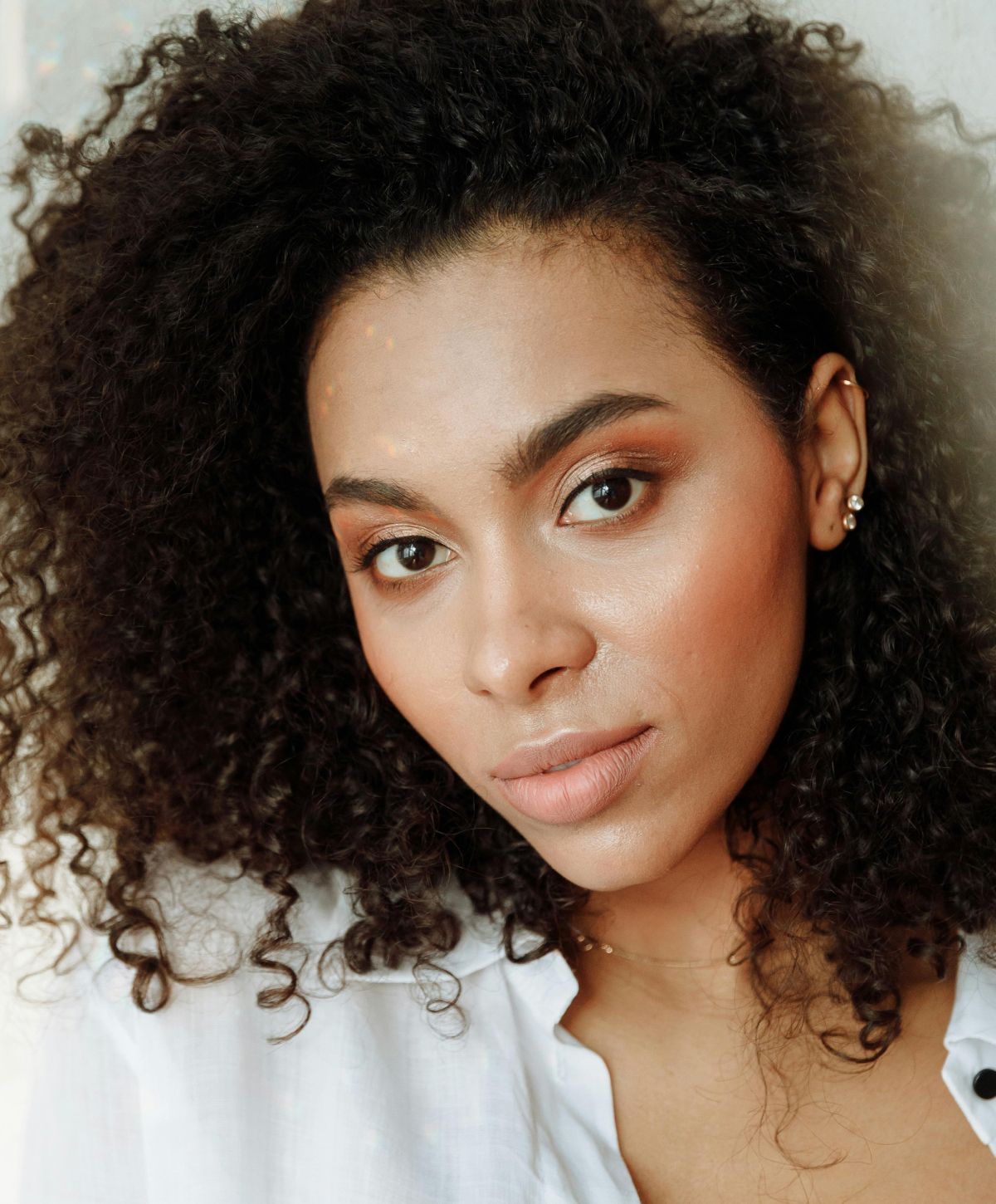 Avon blepharoplasty model with curly hair and natural makeup.