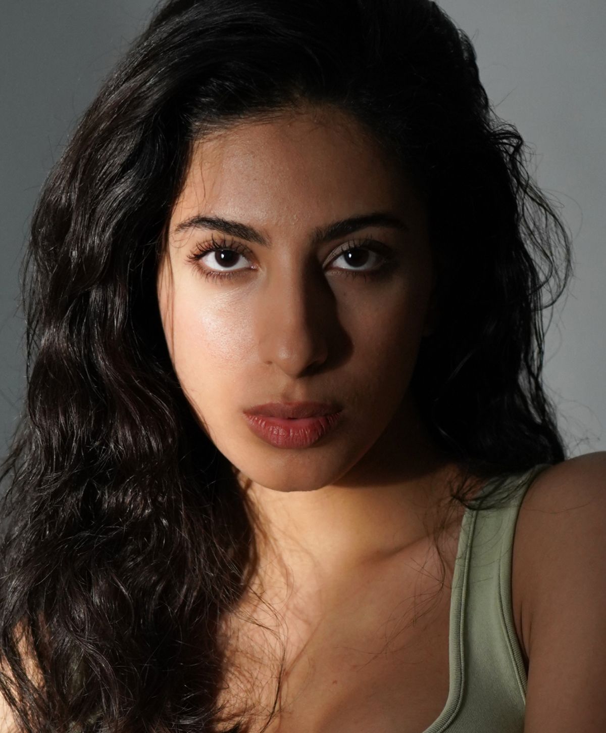 Avon facial liposuction model with wavy hair and intense gaze.