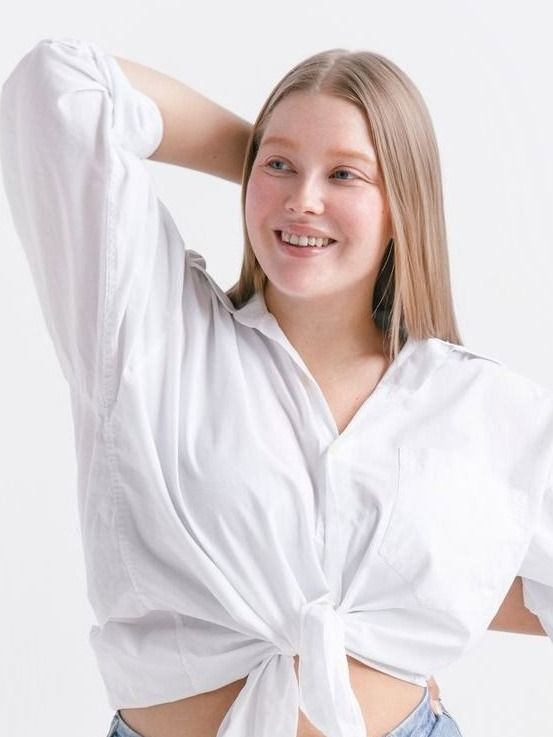 Smiling Avon breast reduction model with long hair in white blouse.