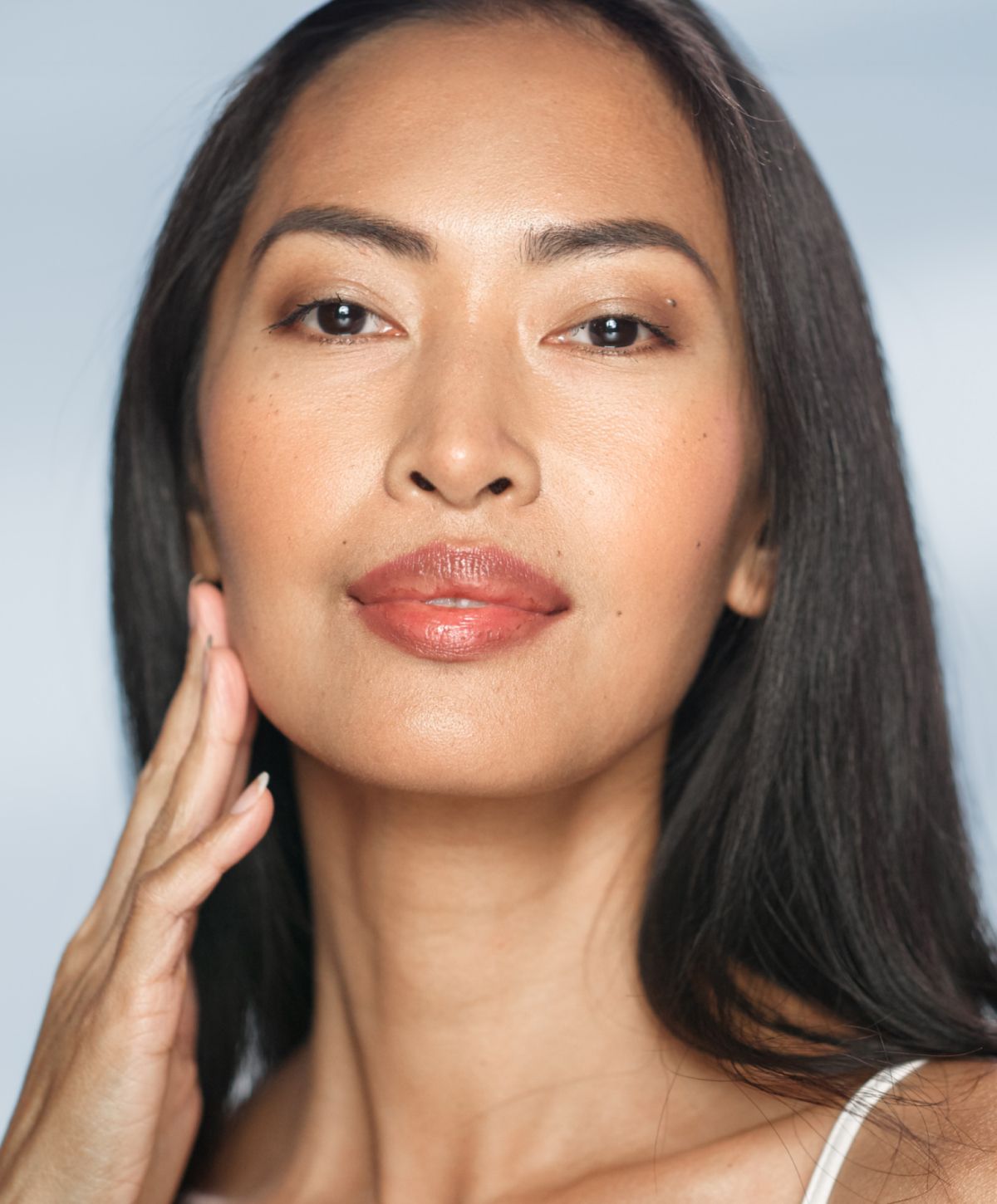 Avon photofacial model with long hair, natural makeup, smiling gently.