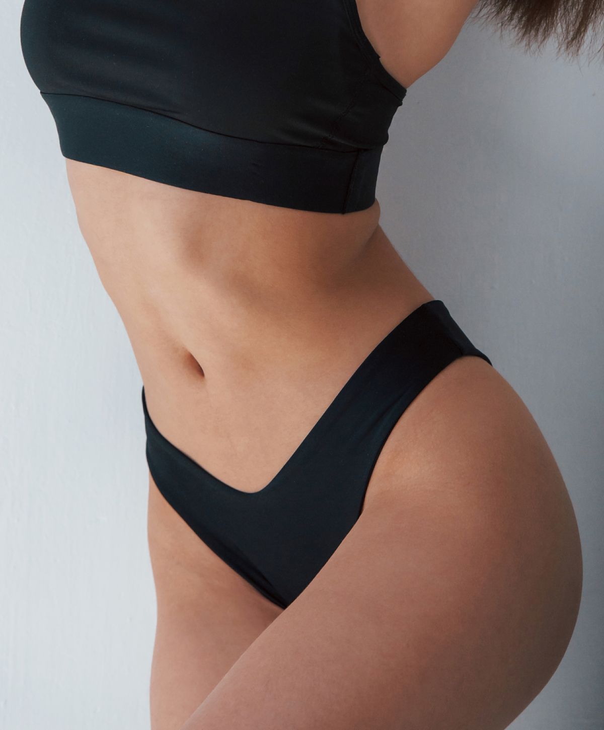 Farmington abdominoplasty model wearing a black crop top and bikini.