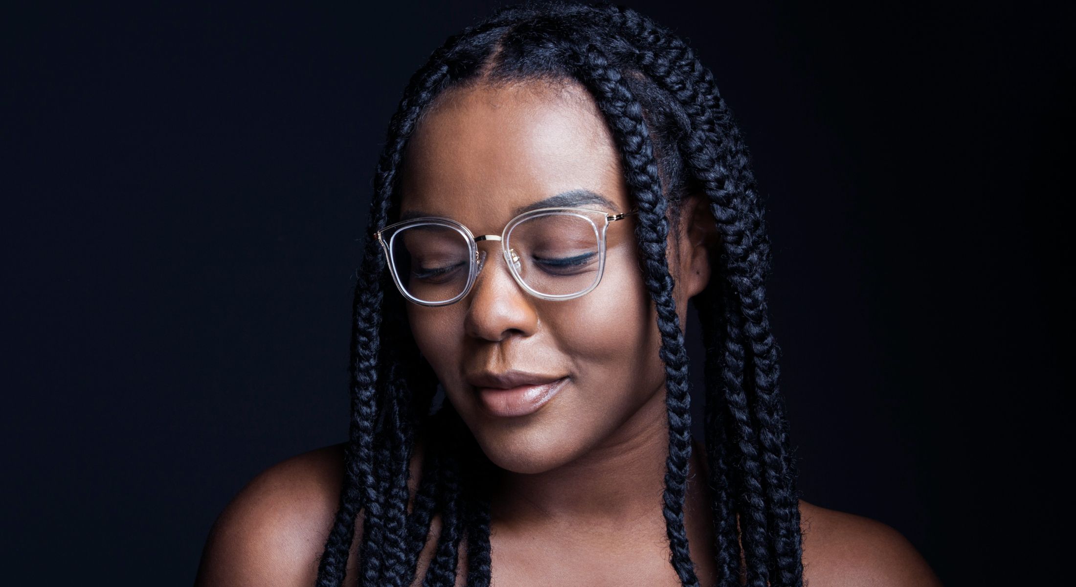 Woman with braided hair and glasses, serene expression.